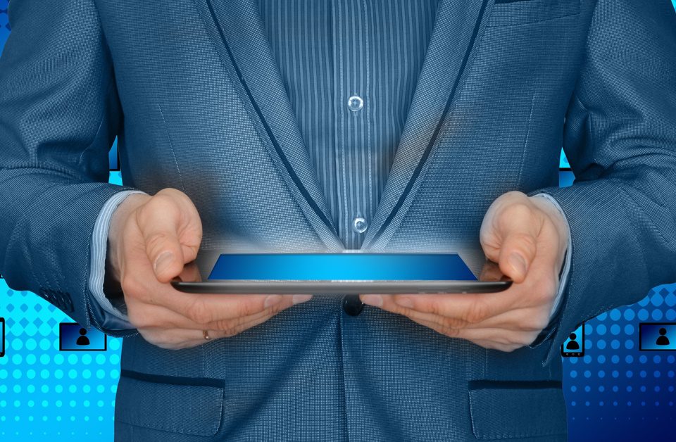 This picture is of a man in a suit holding a laptop and it indicates the importance of asking questions for new safety management system success.