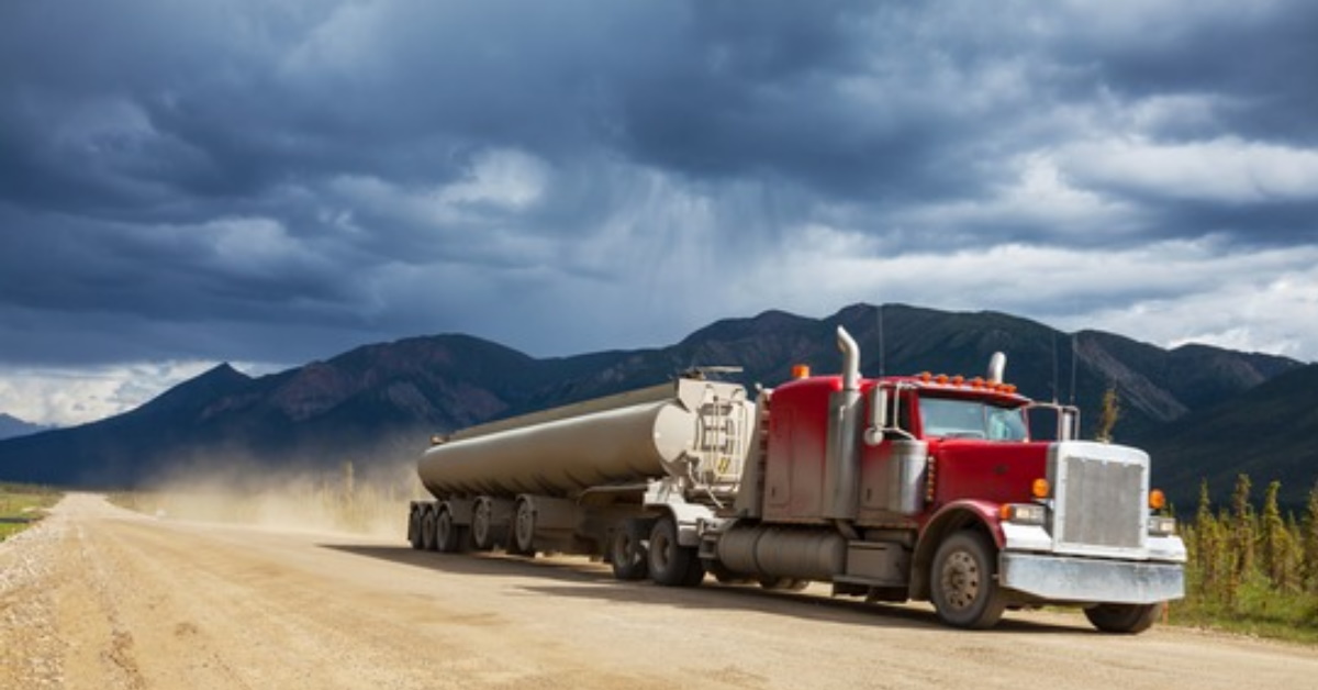 Picture of a truck driving safely on a highway in the mountains which indicates they have a HSE or safety program, system, and manual